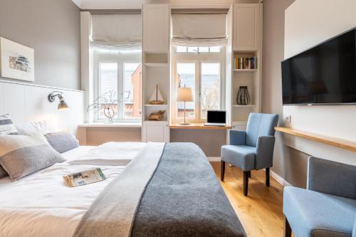 um quarto com uma cama, uma cadeira e uma televisão em Logierhaus K15 Appartement 6 em Borkum