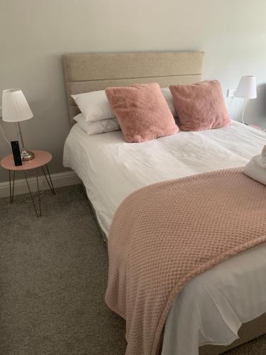 una camera da letto con un letto con cuscini rosa e un tavolo di Newton House ad Alstonfield
