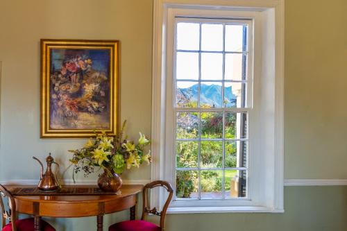 ein Fenster in einem Zimmer mit einem Holztisch mit Stühlen und einem Siddx-Tisch in der Unterkunft Die Waenhuis Guest House in George