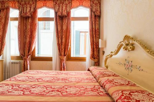 a bedroom with a bed and two windows at Locanda Al Leon in Venice