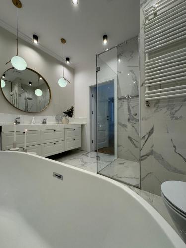 a bathroom with a tub and a sink and a mirror at Wilson Apartamenty in Poznań