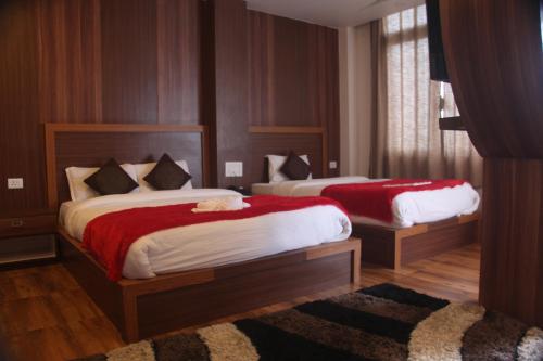 a bedroom with two beds with red sheets at East On Blue Hotel in Ilām