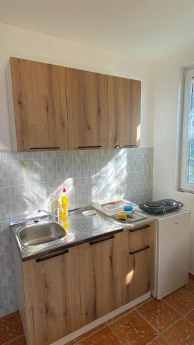 a kitchen with wooden cabinets and a sink at Extra lokacija!!!!! in Sutomore