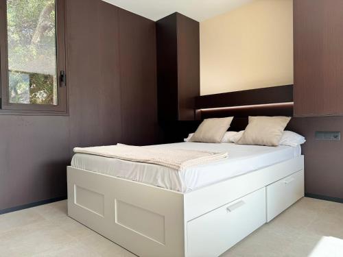 a bedroom with a white bed with a wooden headboard at Camping Fonts del Algar in Callosa de Ensarriá