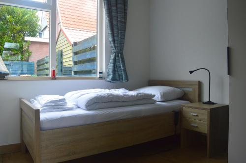 a bed in a room with a window at Vakantiehuisje Te Gast op Texel in Den Burg