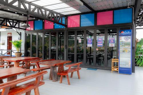 un restaurant avec des tables en bois, des bancs et des fenêtres dans l'établissement Onjira Resort, 
