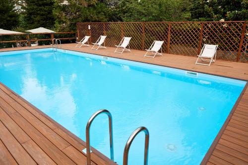 a swimming pool with four chairs and a deck with at Occidental Aurelia in Rome