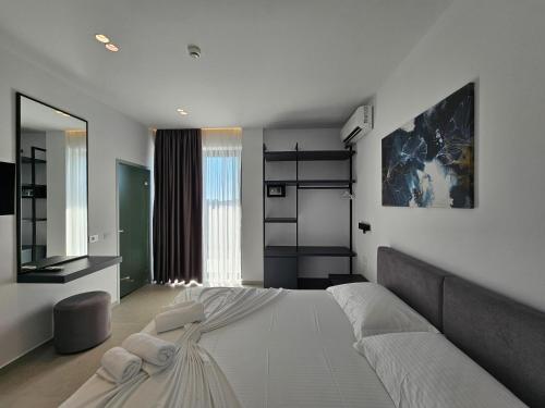 ein Schlafzimmer mit einem großen weißen Bett und einem Spiegel in der Unterkunft Adele Hotel Ksamil in Ksamil