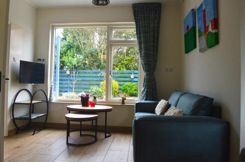 a living room with a couch and a window at Vakantiehuisje Te Gast op Texel in Den Burg