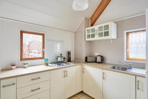 a kitchen with white cabinets and a sink at À 800m de la plage, chalet cosy pour 4 in Loctudy