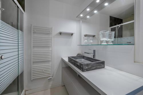 une salle de bain blanche avec un lavabo et un miroir dans l'établissement 200m du Port du Pouliguen - 700m plage du Nau, au Pouliguen