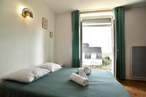 ein Schlafzimmer mit einem Bett mit zwei Kissen und einem Fenster in der Unterkunft Bruyères - Appartement vue mer à 150m de la plage in Saint-Cast-le-Guildo