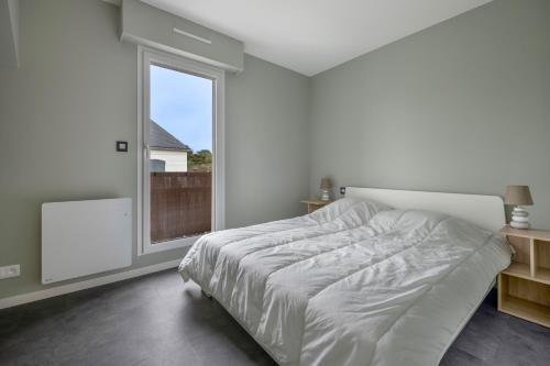 a white bedroom with a large bed and a window at Viree en famille a Pornichet in Pornichet