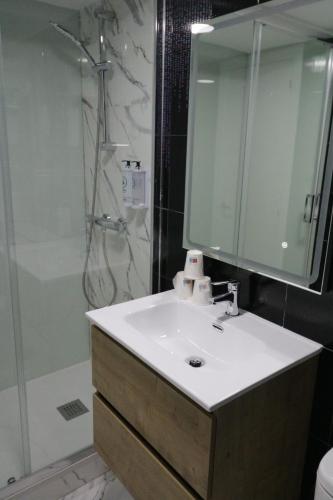 a bathroom with a sink and a shower with a mirror at Hostal Alda Palencia Plaza in Palencia