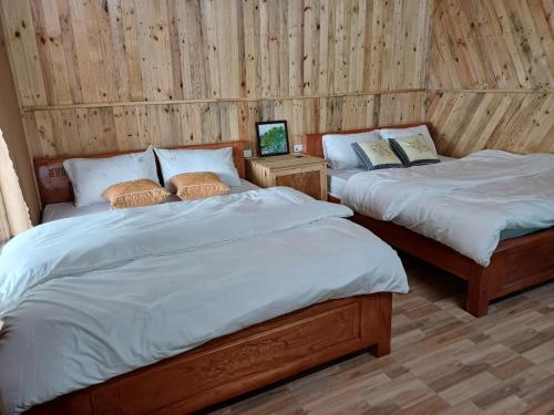 two beds in a room with wooden walls at Hill House in Mai Chau
