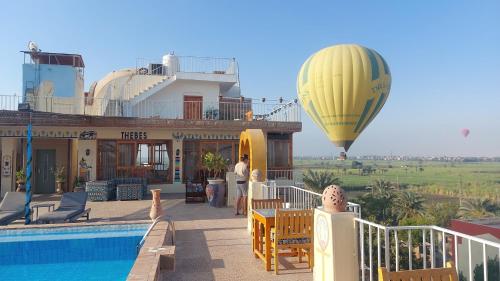 a hot air balloon flying over a building with a pool at Thebes Hotel in Luxor