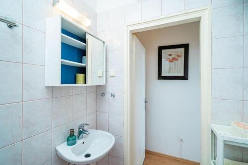 W białej łazience znajduje się umywalka i lustro. w obiekcie Lero Sea View Apartment w Dubrowniku
