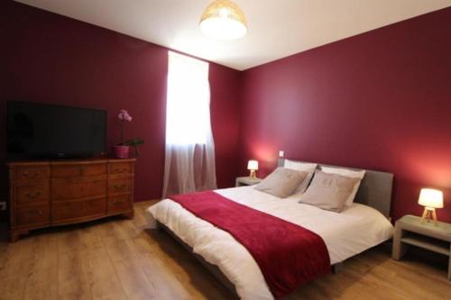 une chambre avec un grand lit avec un mur rouge dans l'établissement Petit appartement confortable, à Châteaubourg