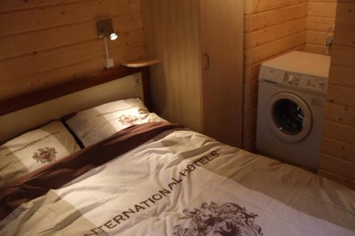 een bed in een kleine kamer met een wasmachine bij Chalet Ermelo in Ermelo
