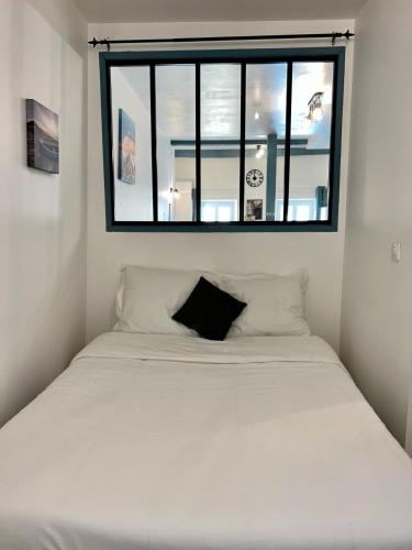a bedroom with a white bed with a window at Le Palantin in Le Palais
