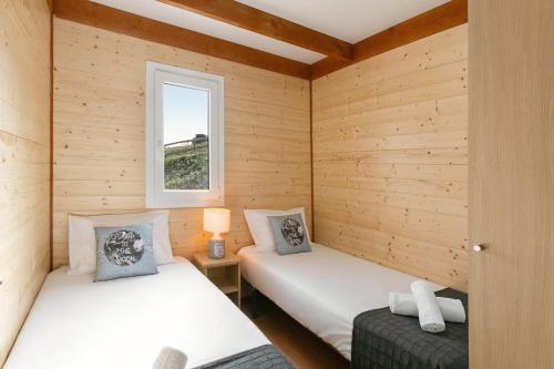 2 łóżka w pokoju z drewnianymi ścianami w obiekcie Quinta dos Castanheiros w mieście Usseira