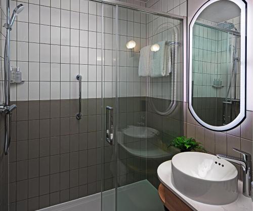a bathroom with a sink and a shower and a mirror at Leonardo Hotel Dublin Parnell Street - Formerly Jurys Inn in Dublin