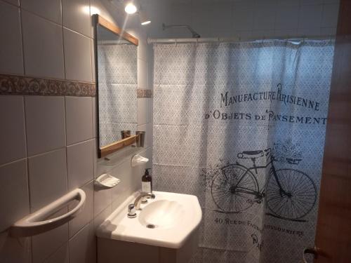 a bathroom with a sink and a shower curtain with a bike on it at Departamento dos dormitorios con cochera Tres Arroyos -3- in Tres Arroyos