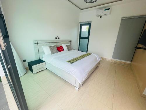 a bedroom with a white bed with a red pillow at Les merveilles d’assinie in Assinie