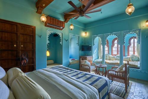 a bedroom with blue walls and a bed with chairs at Kaladwas Lal Haveli - A Heritage Boutique Hotel in Udaipur