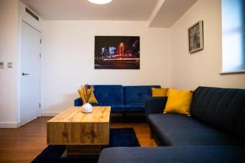 a living room with a blue couch and a coffee table at Close To Leeds City, Spacious, Sleeps 4, in Beeston Hill