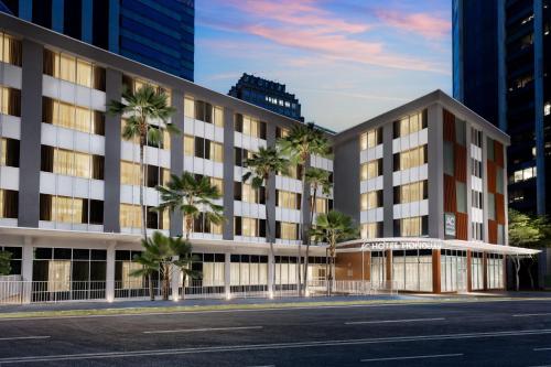 an office building with palm trees in a city at AC Hotel by Marriott Honolulu in Honolulu