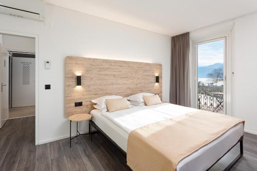 a bedroom with a large bed and a large window at Hotel Du Lac in Locarno