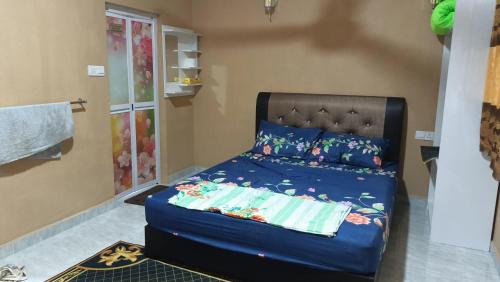 a bedroom with a bed with a blue comforter at Teratak Cikgu Homestay in Pasir Puteh