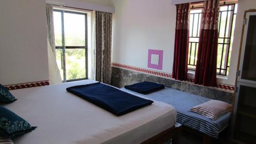 a bedroom with two beds and two windows at Mahabala Valley Guest House in Gokarna