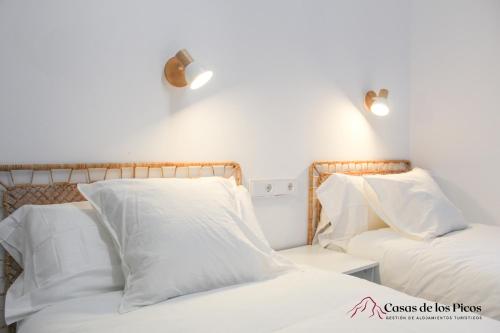 a bedroom with two beds with white pillows at Apartamento rural Karibu 2 San Esteban by Casas de Los Picos Ecoturismo en los Picos de Europa in San Esteban