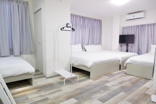 ein weißes Schlafzimmer mit 2 Betten und einem Spiegel in der Unterkunft GLOU Minami Koiwa in Tokio