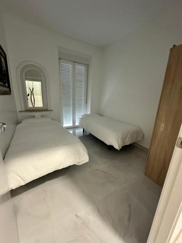 two beds in a white room with a window at Rambla Alicante in Alicante