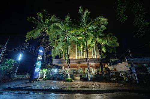 a building with palm trees in front of it at night at Cygnett Inn Celestiial Goa in Candolim