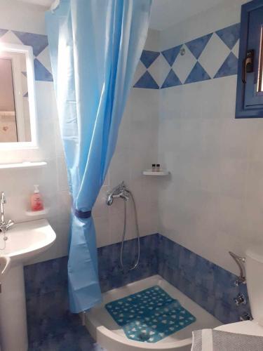 a bathroom with a shower with a blue shower curtain at Pansion Giorgos & Rania in Skiathos