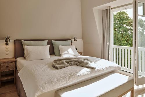 a white bedroom with a bed with a window at The Cozy Hotel & Lofts Timmendorfer Strand in Timmendorfer Strand