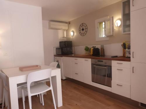 a kitchen with white cabinets and a white table and chairs at GASETIENNE Mazet T2 dans domaine avec piscines et tennis in Gassin