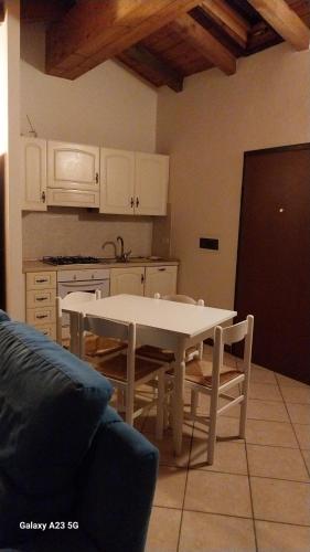 een keuken met een witte tafel en een tafel en stoelen bij La corte dei celti la fonte 1 in San Benedetto Del Querceto