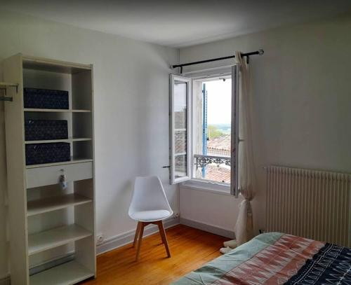 een slaapkamer met een bed, een stoel en een raam bij Les Hirondelles Archiac in Archiac