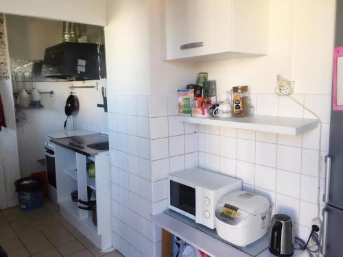 una pequeña cocina con una pared de azulejos blancos en Chambre ensoleillée et lumineuse en Orly