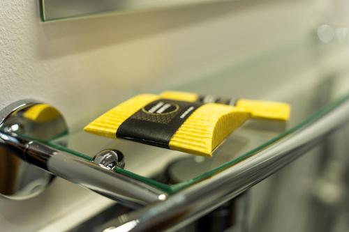 a yellow and black cleaning sponge sitting on a glass shelf at Elegant Apartments in Poznań