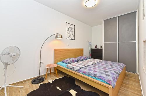 a bedroom with a bed and a floor fan at Apartment Loborika 1411 in Loborika
