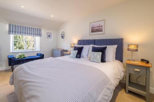 a bedroom with a large bed with a blue headboard at Three Tuns Cottage in Little Walsingham
