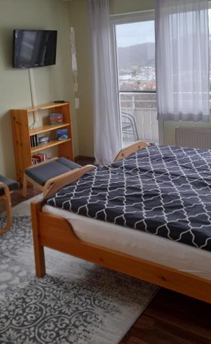 a bedroom with a bed and a window with a television at Apartments Panoramablick in Geislingen an der Steige