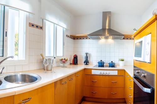 a kitchen with wooden cabinets and a sink and a stove at Villa Blanc in Sa Caleta