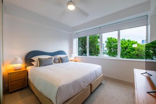 a bedroom with a bed and a large window at Riverside apartment with city & Story Bridge view in Brisbane